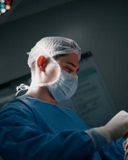 Dr. Renato Carvalho Santos in surgical attire in the operating room, under directional light